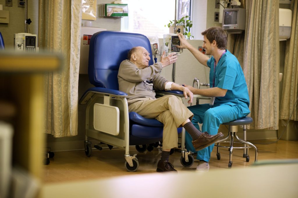 Male Nurse Checking Senior Patient In Hospital