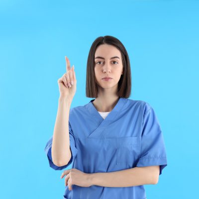 Attractive female trainee nurse on blue background